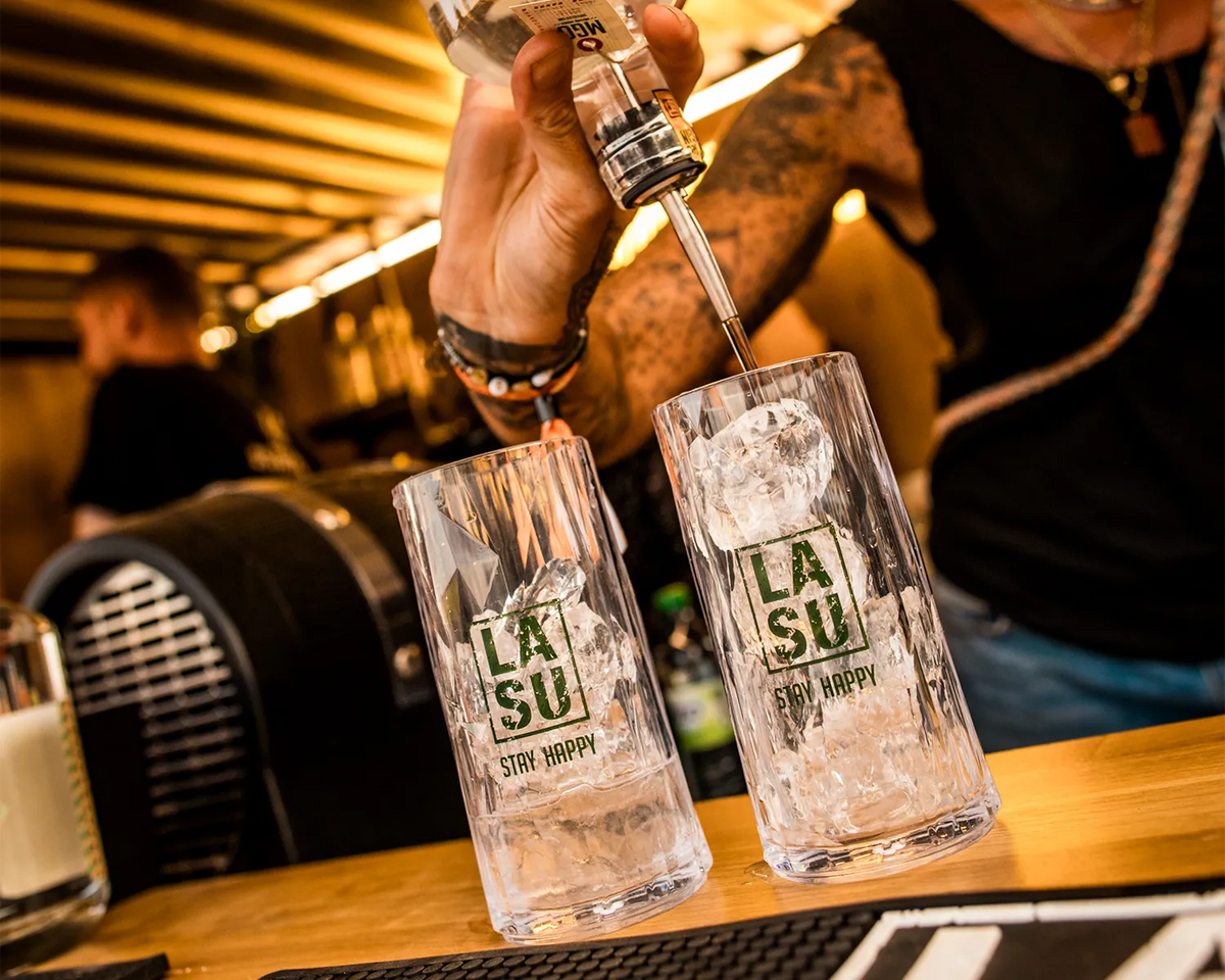 Barkeeper gießt Gin aus MGO-Flasche in zwei LA SU Gläser mit Eis