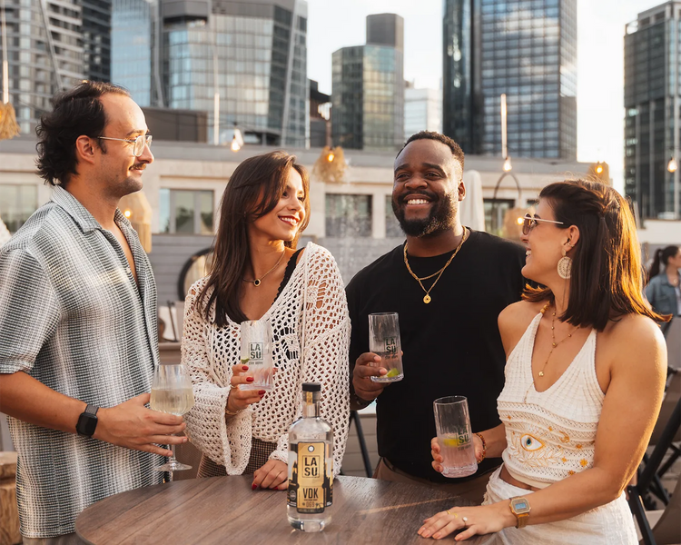 Gruppe stößt mit LA SU VDK auf Rooftop-Terrasse vor Skyline an